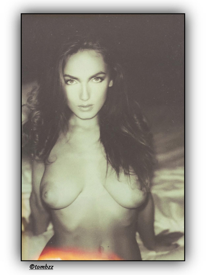 An analog portrait of a woman with long, freely cascading hair, posed in softness and stillness. Her gaze is thoughtful, elusive, caught somewhere between dream and memory. Subtle nudity blends into the mood of the image — not as display, but as a natural part of its melancholic narrative. The background dissolves into darkness, while sepia-toned light emphasizes the intimacy and vintage character of the photograph.