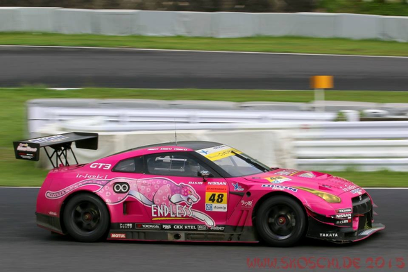 Ein pink beklebter Nissan GT3 Rennwagen mit Fahrtrichtung rechts.
Der Hintergrund ist leicht verwischt.