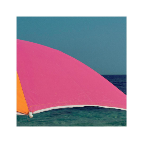a closeup scene of a colorful sun umbrella at the beach. in the background two shades of blue are visible, a slightly more turquoise tone for the sky and a darker tone for the ocean