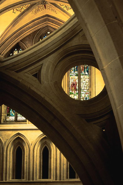 Interior of Wells cathedral: looking through a circle of the famous scissor arches to a stained-glass window.