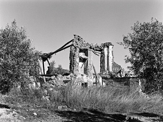 The ruins of an abandoned Cortijo. Just parts of stone wall and two timber roof beams remain standing. 