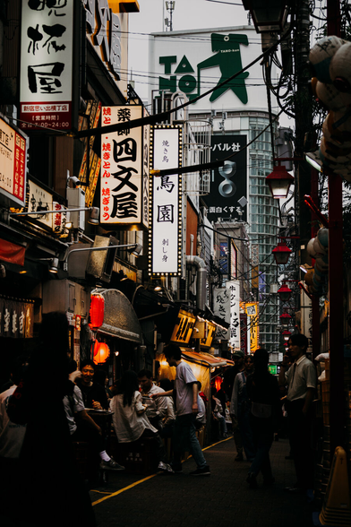 photo of a narrow street of Shinjuku at dawn with a lot of light billboards at the buildings