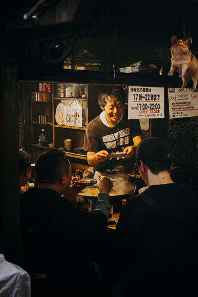 photo of a chef reaching food to a customer in a very small japanese restaurant