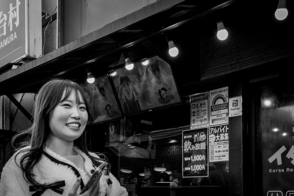 Noia somrient mentre camina per un carrer de Shin-okubo (Tòquio)
