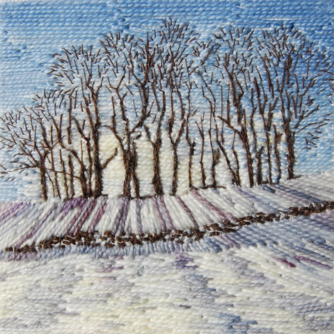 Stitched artwork depicting a stabd of bare trees on a snow covered hillside