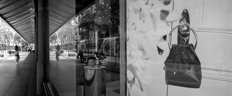 Black and white panoramic film photo of a shop window and window shopper in Sydney for the Ambiguous Zine. Agent Shadow 35mm film and the Horizon Perfekt camera. 
