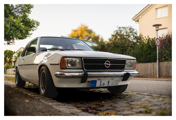 Weißer 70er Jahre Oldtimer (Opel Ascona) von schräg tief vorn fotografiert. 