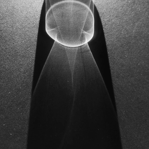 The nun

Photo: Sunlight passing through a glass on a black office table. Part of the shadow turns a deeper black around the figures made from light being diffracted through water and glass. In this case the deep shadow looks like a cowl around a rudimentary round "head" and "torso".