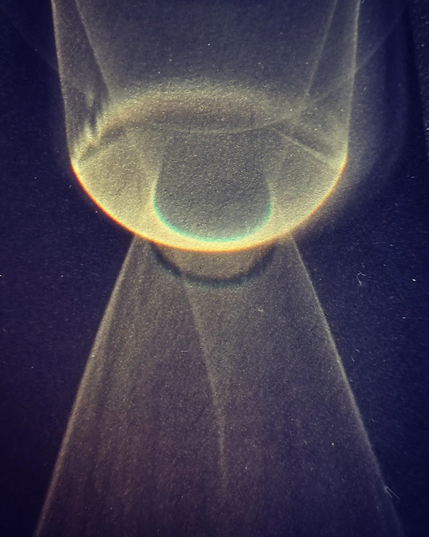 The Eye of the Sun

Photo: Sunlight passing through a glass on a black office table. Part of the shadow turns a deeper black around the figures made from light being diffracted through water and glass.

Here a tunnel shape w rounded end (from above) seems to overlap with a pointy narrow mountain (from below). The intersection looks like a dark iris in an eye of yellow light