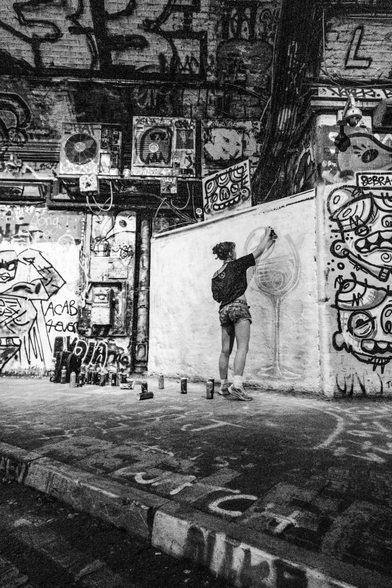 A monochrome photograph depicts a graffiti artist.