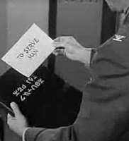 A human hand holds a translation of an alien book title.  It reads: "To Serve Man".
