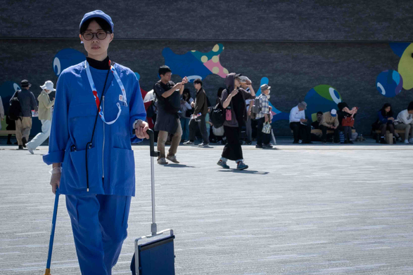 Dona del servei de neteja, amb uniforme blau, porta una escombra i un recollidor.