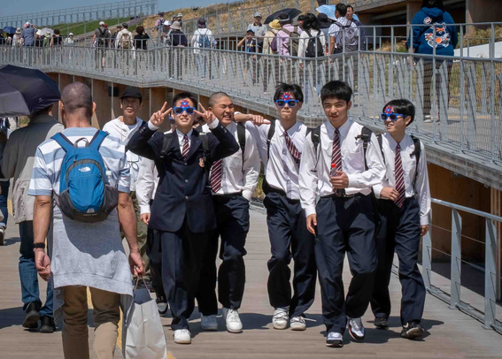 Grup d'estudiants de batxillerat, amb ulleres commemoratives de l'Expo, un d'ells en veure's fotografiat fa el signe de la victòria, un costum molt estès al Japó quan es fan fotos en grup. 