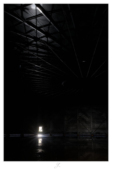 A portrait image with very strong contrasts. The picture was taken in an old gasometer, the floor of which is covered with water. The scene is very dark and shows a window-like opening at the other end of the image. Sunlight falls through this window and casts a star-like reflection on the dark surface of the water. The light reflection also casts a spot on the bottom of the old gas storage in the upper part of the picture. It lightens a strong metal structure that supports the bottom of the gas storage.

Greetings to @marion4life@mastodon.art

AI disclaimer: Using my work, its meta data, written or derived description to create media with or train AI based systems is prohibited.