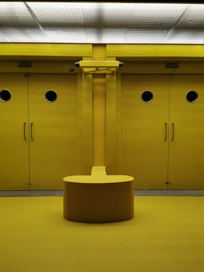 A vibrant yellow interior featuring a round bench and circular door windows.
