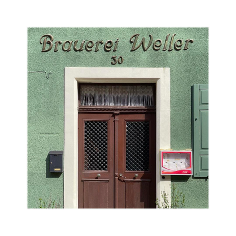 a straight look at the green facade of an old restaurant. the name is painted above the door, on the left side is a postbox, on the right side a display of the menu