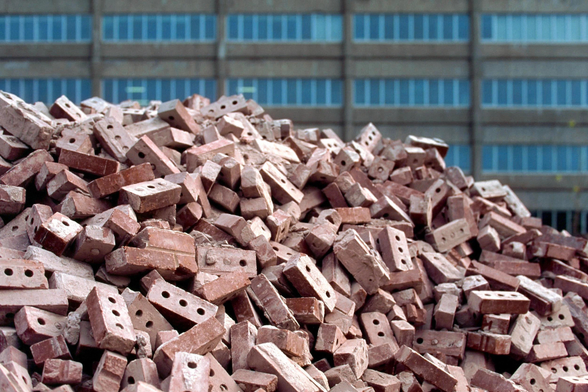 A stack of bricks in front of an ageing building.