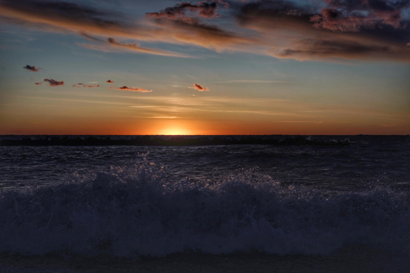 Sonnenuntergang über der Ostsee, die Sonne ist schon fast ganz verschwunden, am Himmel rosa Wolkenbänder