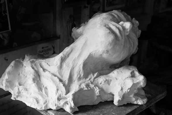 A black-and-white photograph of a plaster bust of a woman. The woman lies with her head tilted to the right, backward. The bottom of the statue is unfinished. The light originates from the left and falls on her turned neck and chin. It creates a dramatic image, as if the woman is suffering.