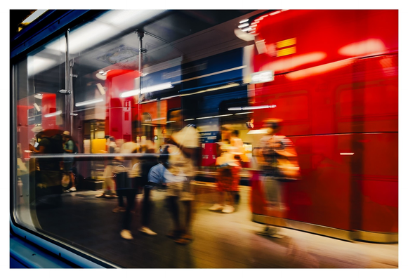 S-Bahnhofszene in München. Menschen warten draußen vor dem Zug. Durch Bewegungsunschärfe und Reflexionen an der Scheibe wirkt das Bild stark verfremdet, abstrahiert und ein wenig wie gemalt.