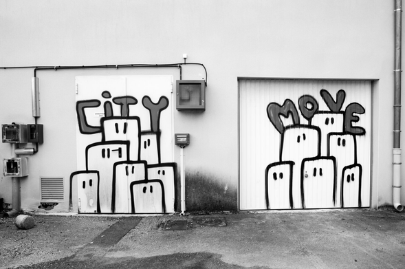 Graffiti on garage doors depicting buildings with eyes and the text ‘city move’. (Version françæ) Graffitis sur des portes de garage représentant des immeubles avec des yeux, ainsi que læ texte 'city move', qui pourrait signifier 'mouvement de ville', ou 'déménagement en ville', ou …?