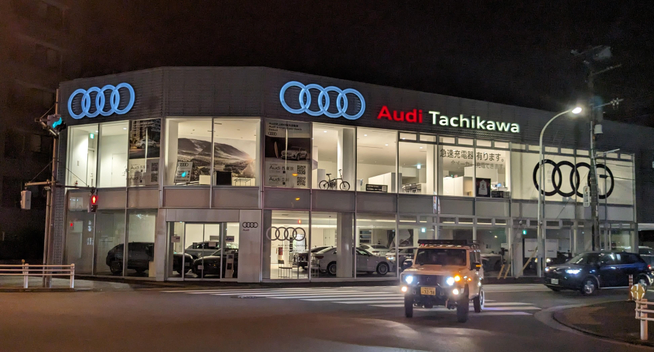 Ein Autohaus eines deutschen Herstellers an einer Kreuzung bei Nacht in Tachikawa.