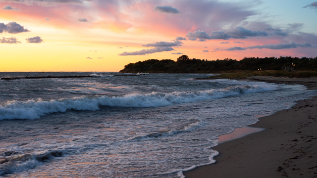 Farbfoto im Panoramaformat. Rot-rosa-orangefarbener Himmel über der Ostsee.