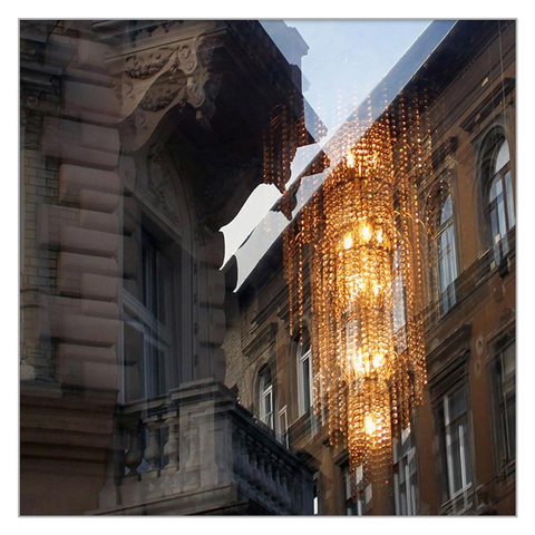 The window of the downtown restaurant reflects the picture from the other house, and the glowing chandelier is visible outside. 