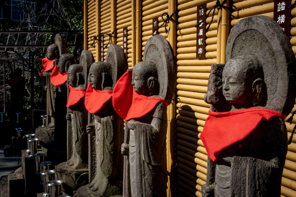 Detall de deïtats en un temple budista, totes abillades amb un mocador de coll vermell.