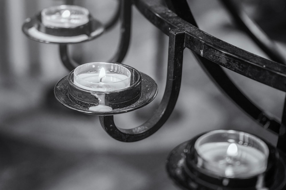 Close up of three wax candles in metal holders in a cathedral in Iceland.