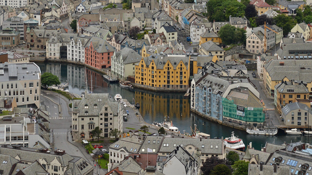 A photo looking down at the strait Ålesundet going through the town of Ålesund. The strait is lined with buildings of different colors.
