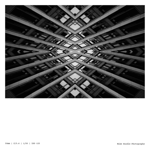 An abstract black and white photo of a symmetrical architecture structure with lots of silver lines and shapes.