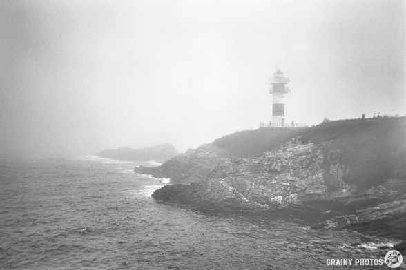 A black-and-white film photo of the Illa Pancha lighthouse in Ribadeo on a foggy day