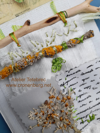 The zoom on the abstract collage shows the two wooden sticks and the embroidered real grey lichen on a background of textile scraps and intuitive embroidery. One stick is lemon tree without bark, the stick with bark is cobered with a bright orange lichen. This colour is repeated in the stitches on the real grey lichen.