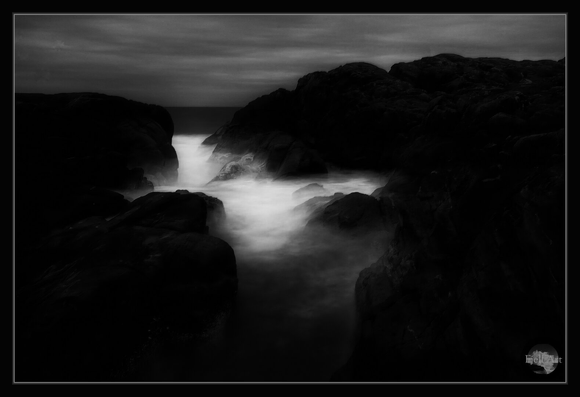 Waves between the rocks in black and white. Dark Art.