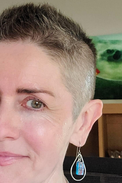 A female with a buzz cut and a dangling earring.