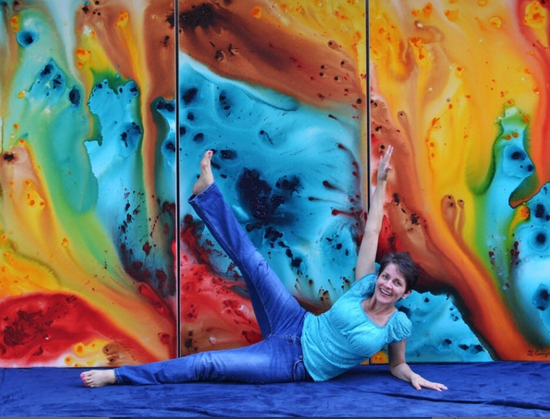 Colorful abstract art with artist Sharon Cummings smiling and doing a yoga pose in the front.