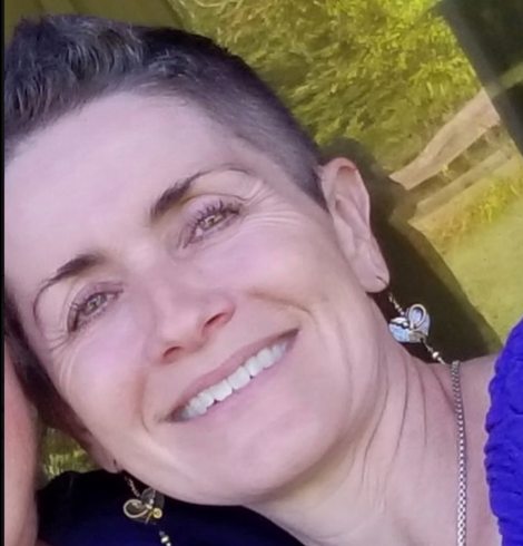 picture of white female with very short brunette hair and green eyes smiling.