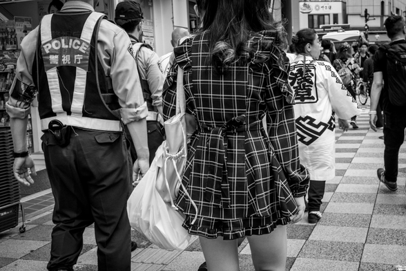 Noia amb vestit de quadres amb minifaldilla al costat d'un policia.