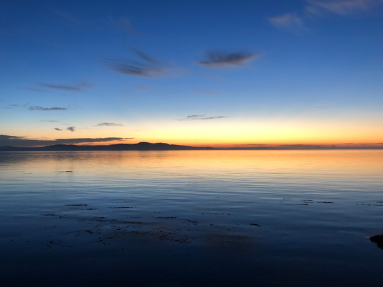 Sun not quite visible behind eastern islands. Red sky and reflection on water