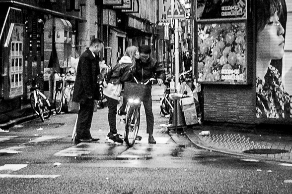 Una dona s'atansa a un home muntat en una bicicleta per fer/li un petó al barri de Kabukicho, Tòquio.