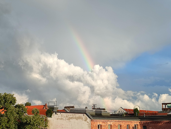 Regenbogen scheint aus einer sehr flauschigen weißen Wolkenwand aufzusteigen