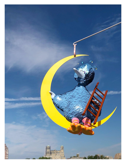 Closeup of a portion of Alex Da Corte’s kinetic sculpture “As Long as the Sun Lasts,” displayed on the roof of the Metropolitan Museum in NYC in 2021. It features Big Bird with blue feathers sitting in a suspended crescent moon and holding a ladder, as he gazes up into a blue sky with clouds. Tiny buildings can be seen in the distance at bottom frame.

From the Met Museum website: “The work is comprised of a base with three interlocking pieces and a mobile component that sways and rotates gently with passing air currents. […] Suspended from near the top of the sculpture, covered in roughly 7,000 individually placed laser-cut aluminum feathers, Big Bird is found perched on a crescent moon with a ladder in hand—suggesting the possibility of passage back to Earth or to other galaxies. Sitting alone, gazing out at the New York skyline, Big Bird has an introspective, melancholic disposition that is amplified by Da Corte’s decision to render the character in blue instead of yellow. This choice of color also gestures to the artist’s personal associations with Big Bird: growing up partially in Venezuela, he watched the Brazilian version of Sesame Street, in which Big Bird’s counterpart, Garibaldo, was blue. The color also alludes to the 1985 film Sesame Street Presents: Follow That Bird, in which the character, while out on a road trip, is captured and painted blue by two carnival operators.”