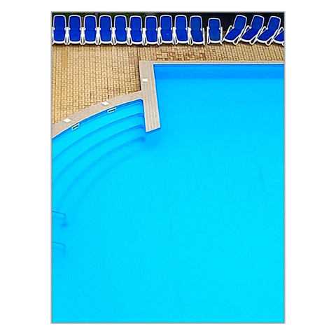 A detail of a swimming pool is photographed from above from a hotel balcony. In the upper part of the image, blue sun loungers are lined up closely together at the edge of the pool.