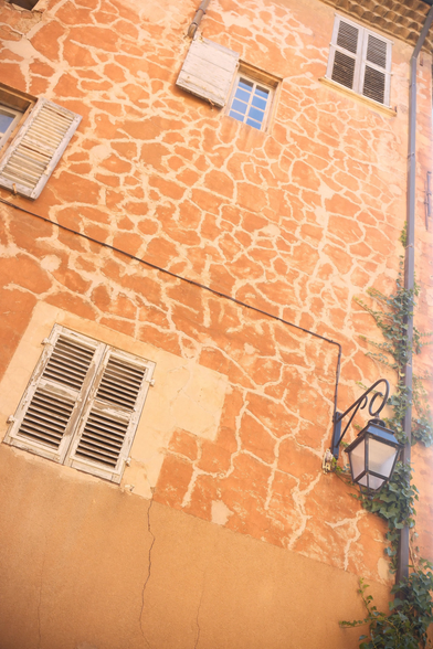 A low angled photo of  building with orange walls stroke by clear random lines, making a giraffe like pattern. Some Windows are irregulary placed on the wall,
