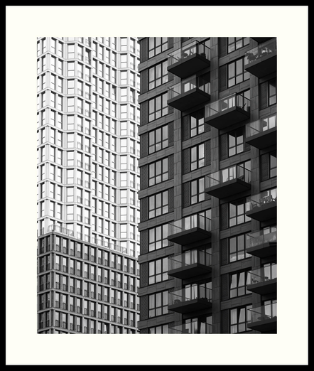 b&w - A tightly framed photo of the De Kroon and Wijnhaven residential towers in downtown The Hague. The building on the left, De Kroon, features a repetition and multitude of floor-to-ceiling windows and its design is inspired by the Chicago skyscrapers from the early 1900s. The building on the right is interspersed with what seems like randomly placed balconies.