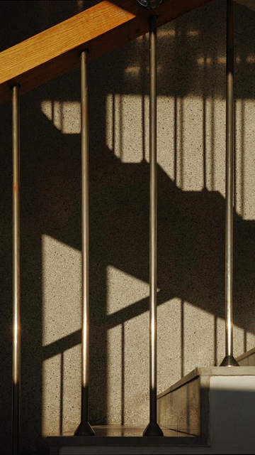 The photo shows a part of a staircase with railings that cast rhythmic shadows.