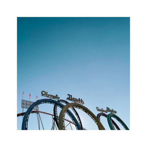 all the loopings of a rollercoaster are visible from a distance. the blue sky that fills up most of the frame is crystal clear