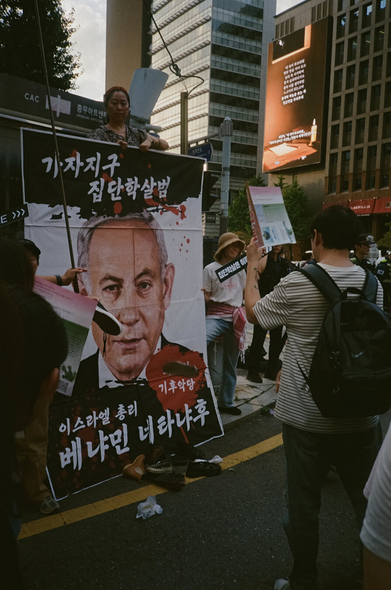 서울 시내를 행진하는 927기후정의행진 참가자들이 “가자지구 집단학살범 기후악당 이스라엘 총리 베냐민 네타냐후”의 대형 사진에 신발을 던지는 규탄 퍼포먼스에 참여하고 있다.