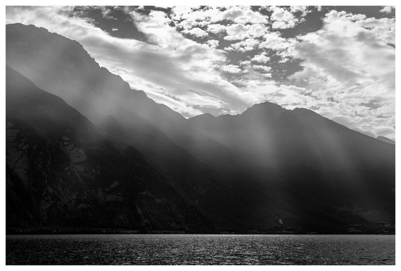 Berge im Dunst an einem See. Dramatisches Schwarzweißbild.